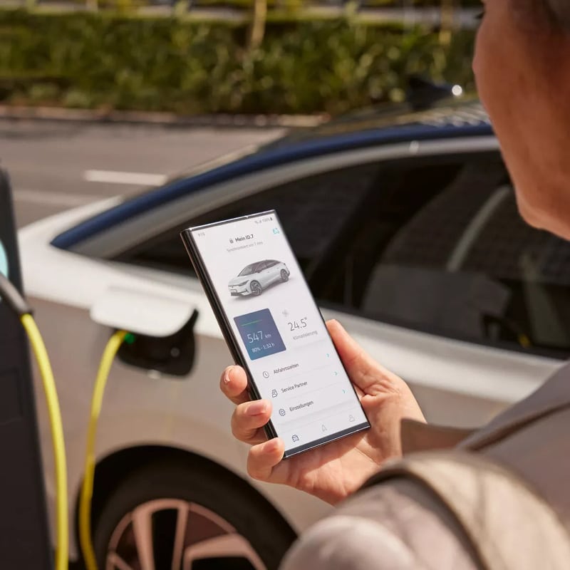 VW ID7 beim Laden. Auf dem Handy wird der Ladestatus angezeigt.